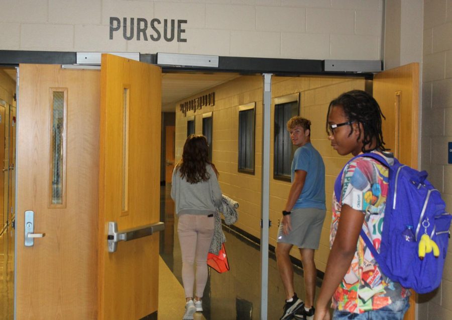 Junior Cameron Everts, sophomore Olivia Zmolik and  sophomore Niko walk through  doors at the front of the school, where they see a daily reminder to pursue greatness. 