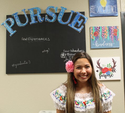 Senior Monica Garza has turned her passion for art and calligraphy into a business opportunity by creating custom paintings for customers. Here, she stands in front of a kindness painting on Ms. Shropshires word art wall. 