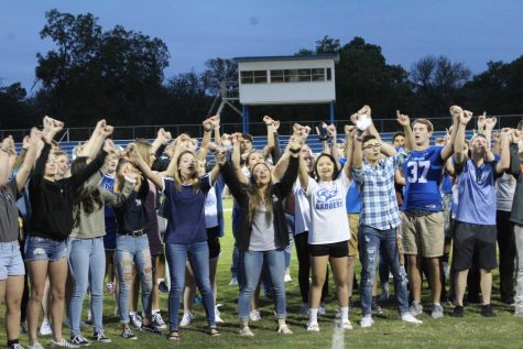 Seniors lock pinkies together as they sing the school song at the homecoming pep rally.