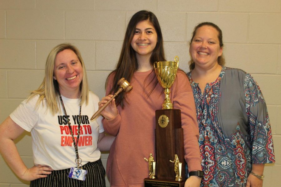 Senior Sena Kucukkarca holds her first place award from the TFA state debate competition alongside her coaches Shelby Randolph and Judith Ann McGhee.