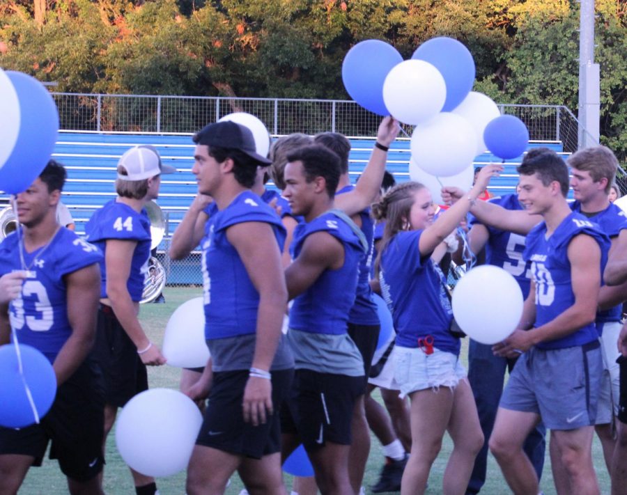 Junior+Megan+Bobo+passes+out+blue+and+white+balloons+for+seniors+to+release+together+at+the+homecoming+pep+rally+on+Wednesday.+