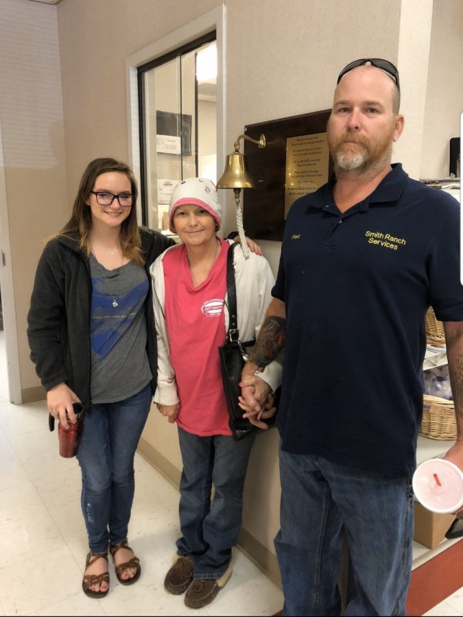Junior Jalena Rostad stands with her mother Julie Bass-Smith and stepfather Fred Smith after Bass-Smith rang the bell signifying her final chemotherapy treatment.  