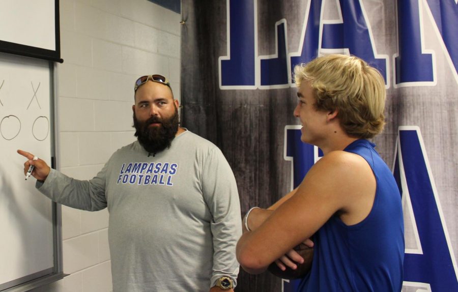 Football coach Tyler Cleavinger discusses plays with quarterback Ace Whitehead before the Taylor game. 