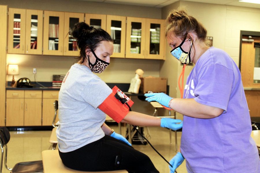 Senior Taylor Talbert takes senior Jacie Newman-Brixius' blood pressure during EMT class. 