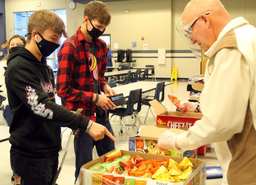 Students buy snacks from principal Joey McQueen during their designated day to mingle in the cafeteria during academic period. 