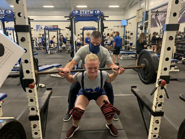 Senior Madelyn Hess squats at powerlifting practice with coach Duane Young Dec. 14. 