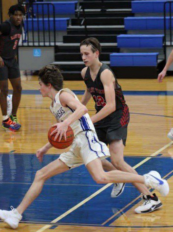 Junior Nate Borchardt dribbles the ball during a basketball game. The team begins their district season tonight. 