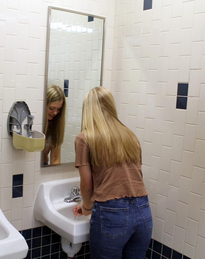 Senior Kaylan Rucker washes her hands next to an empty soap dispenser. Custodians have not refilled the soap because it continues to be stolen due to the devious lick TikTok trend. 