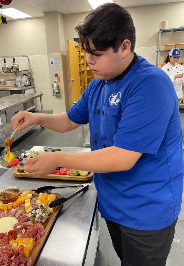 Senior Aaron Martinez serves a fruit plate with honey during the culinary and cosmetology open house Dec. 8.