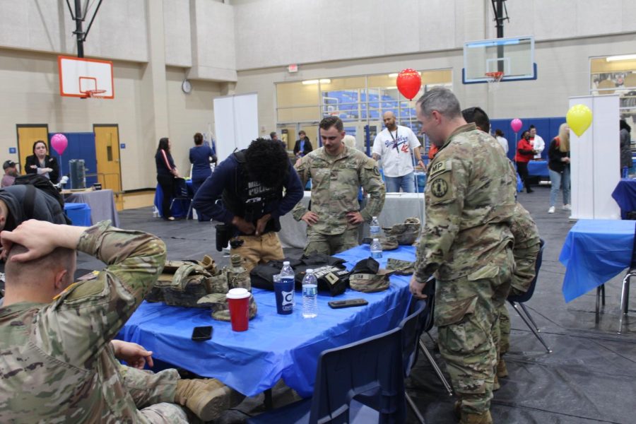 Military men assist a student in trying on equipment at the job fair Feb. 28.
