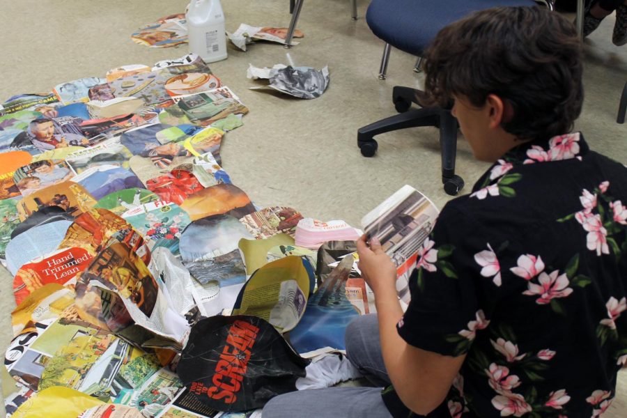 Junior Luke Coonrod cuts out magazine pages to design a mermaid tail for the set of Peter and the Starcatcher. 