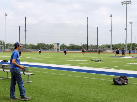 Freshman Jonathan Harris flies a drone to film football practice.