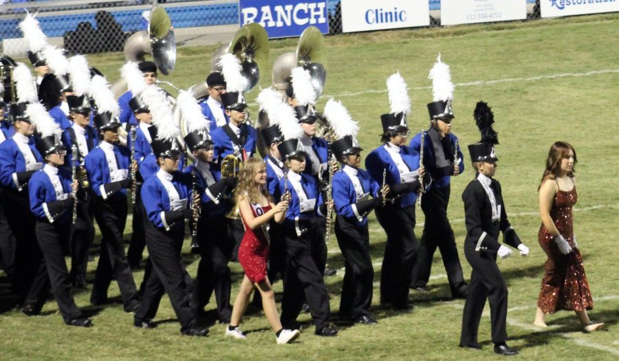 The marching band enters the field fro their performance of Fallen Angel at the Homecoming game Sept. 23. Flute section leader Ella Hairston and drum major Megan Flick wear their homecoming court dresses.