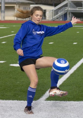 Senior Anna Burgess kicks a soccer ball as part of a warm-up at practice Jan. 23.