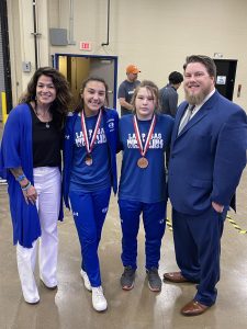 Coach Elma Garnett, junior Charlie Freese, sophomore Taylor Martell, and Coach Donovan Kleckner celebrate after the meet.