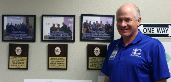 Law enforcement teacher Michael Tatum poses next to plaques won at state.
