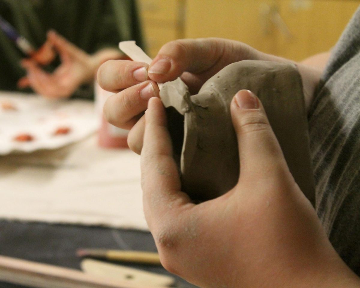 Junior Dean Hannibal works on the neck of his sculpture, smoothing it down in preparation to add the head.