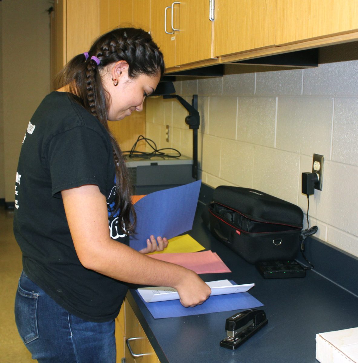 Sophomore Isabell McGinnis staples a script together to be read at Little Badger Camp. 
