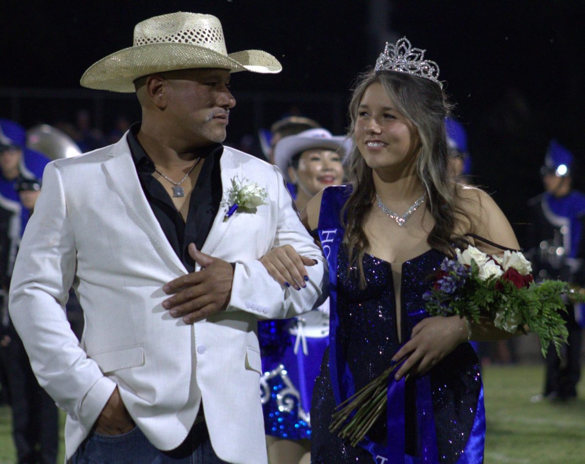 Escorted by her father Robert Resa, senior Jacie Resa celebrates winning homecoming queen during halftime Sept. 26.