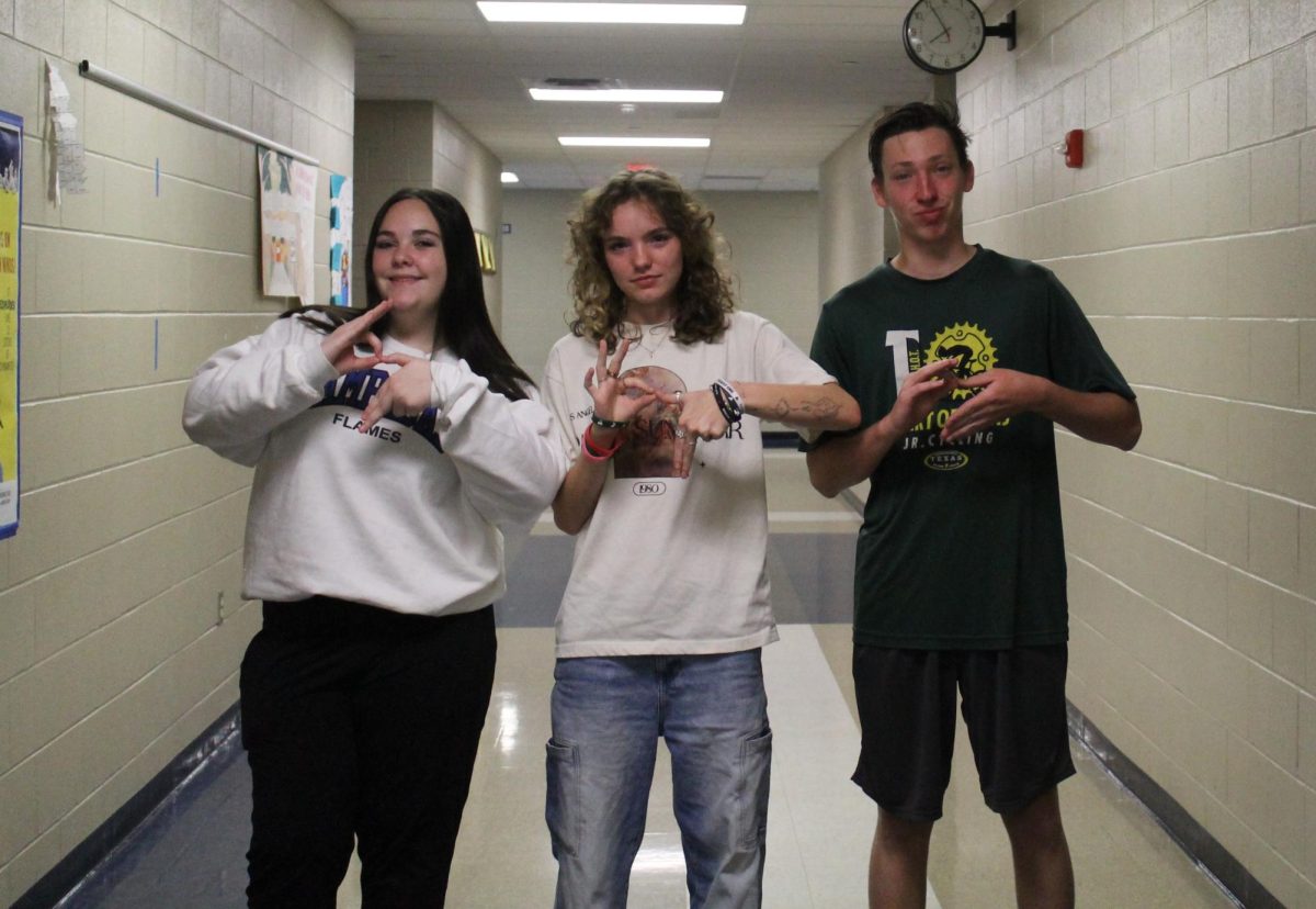 Juniors Teagan Reiss and Ailani Orvis, and senior Gabriel Allison make the 6-7 hand gesture.