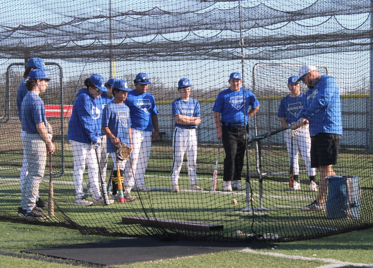 Head baseball coach Chance Evans shows form of swinging during practice Jan. 28. 